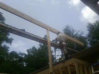 Carpenter setting a ridge beam over a new addition frame — Ice Dam Removal by Roofing Brothers in Basile