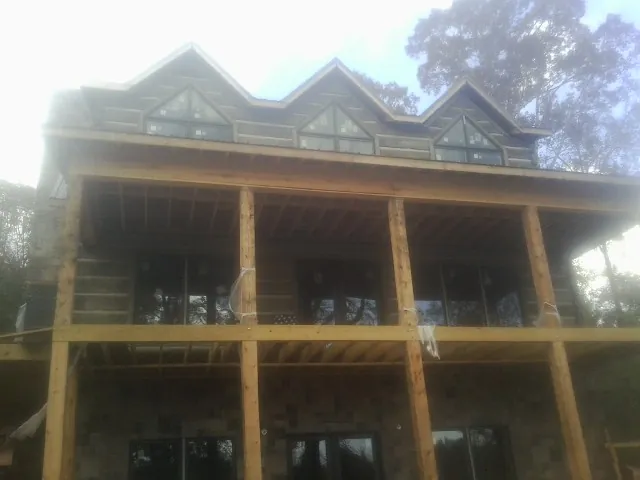 Dormers and porch framing on a large log home under construction — Roof Coating work by our crew in Basile