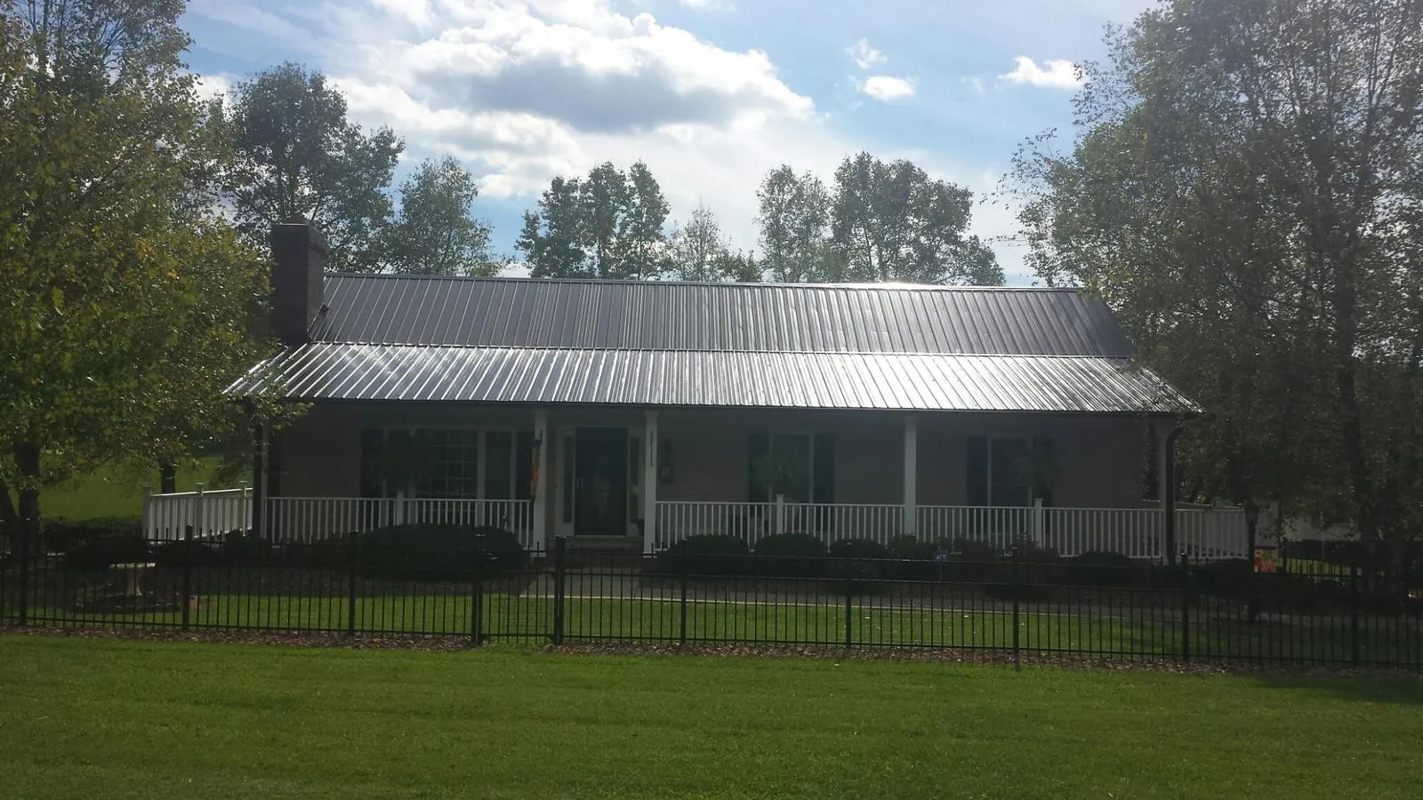 Gray metal roof on a brick ranch with a full width front porch — Gutter Guard Installation work by our crew in Basile