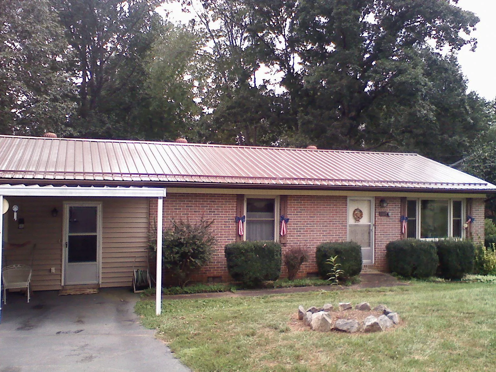 Bronze metal roof and carport on a brick ranch home — Roof Repair work by our crew in Basile